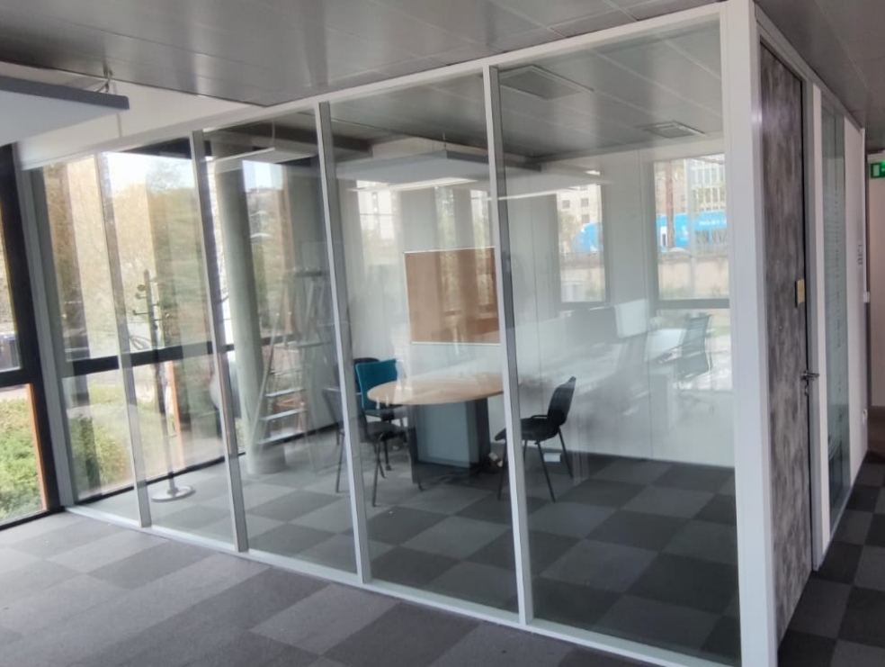 Un bureau au design contemporain avec des cloisons vitrées, permettant la séparation des espaces tout en préservant la sensation d'ouverture et en favorisant la circulation de la lumière naturelle.